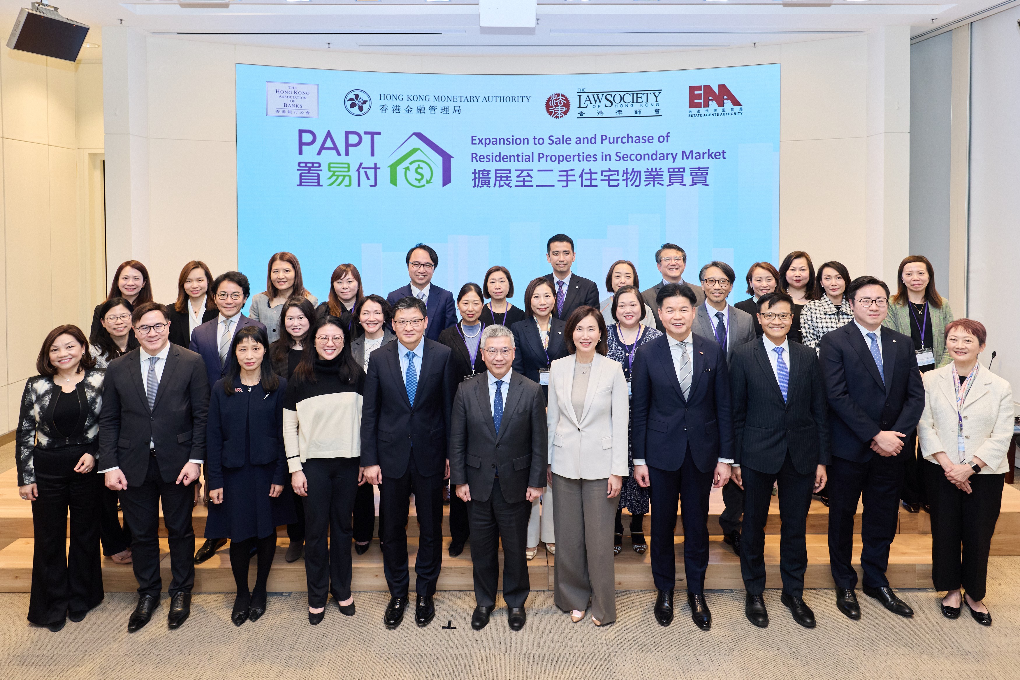 香港金融管理局（金管局）副總裁阮國恒（前排正中）、香港銀行公會主席、中國銀行（香港）有限公司副董事長兼總裁孫煜（前排左五）、香港律師會會長湯文龍（前排右四）、地產代理監管局總監梁德麗（前排左三）、香港上海滙豐銀行有限公司香港區行政總裁伍楊玉如（前排左四）、渣打香港兼大中華及北亞區行政總裁禤惠儀（前排右五）、消費者委員會副總幹事何應富（前排左二）、金管局助理總裁（銀行操守）區毓麟（前排右三）、香港銀行同業結算有限公司行政總裁鄧月容（前排左一）及參與試點計劃的銀行代表出席「置易付」發布會。